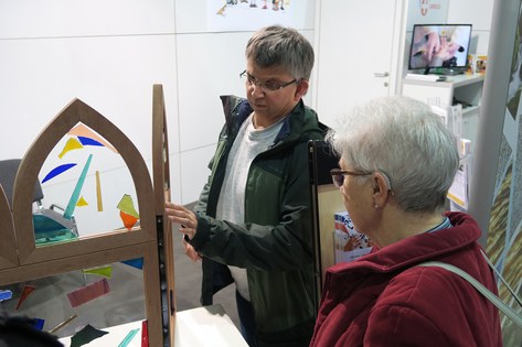 Besucher gestalten ein Kirchenfenster am Stand der Behindertenseelsorge