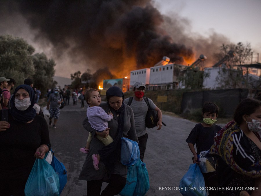 09 September 2020, Greece, Moria: Migrants flee the refugee camp Moria with their belongings after several fires had already almost completely destroyed the camp. This was preceded by unrest among the migrants because the camp had been quarantined since last week after a first case of corona. On Tuesday (08.09.2020) it became known that the number of people infected was over 30. Photo: Socrates Baltagiannis/dpa (KEYSTONE/DPA/Socrates Baltagiannis)